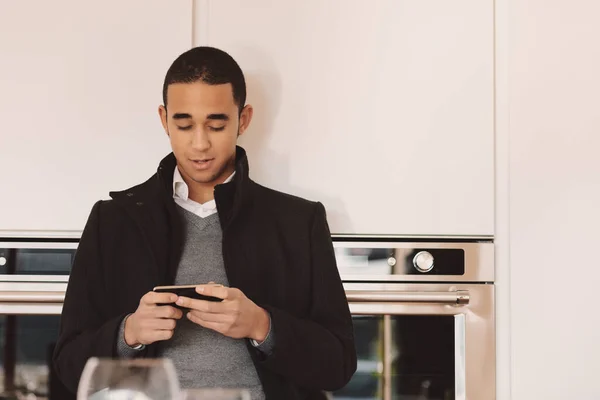 Hombre Joven Abrigo Pie Una Cocina Revisando Teléfono Móvil Para — Foto de Stock