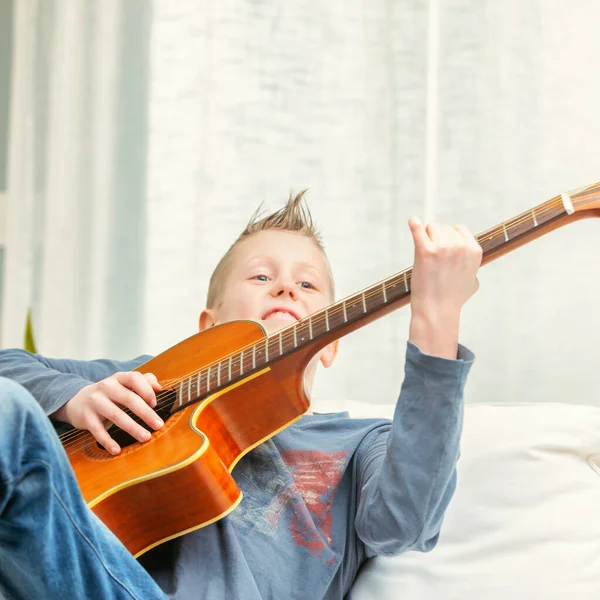 Μουσικό Νεαρό Αγόρι Που Στριφογυρίζει Μια Κιθάρα Στο Σπίτι Καθώς — Φωτογραφία Αρχείου