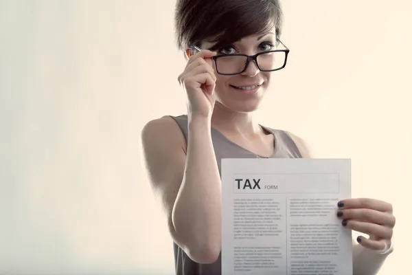 Kobieta Trzymająca Formularz Podatkowy Gdy Patrzy Okulary Przed Kamerą Uśmiechem — Zdjęcie stockowe