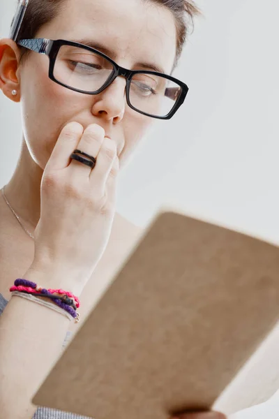 Anxious woman biting her nails as she looks at a journal or diary in a close up low angle cropped image on white