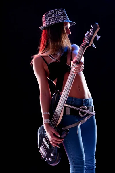 Hipster young rock star female guitarist performing on stage in a chic outfit with sequinned hat in a side view portrait playing electric guitar