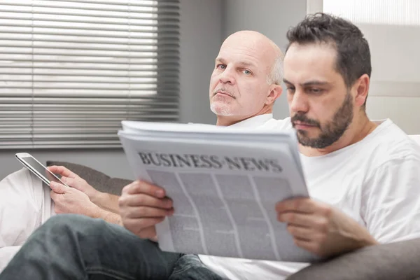 Uomo Seduto Leggere Business News Vicino Con Espressione Preoccupata Osservata — Foto Stock