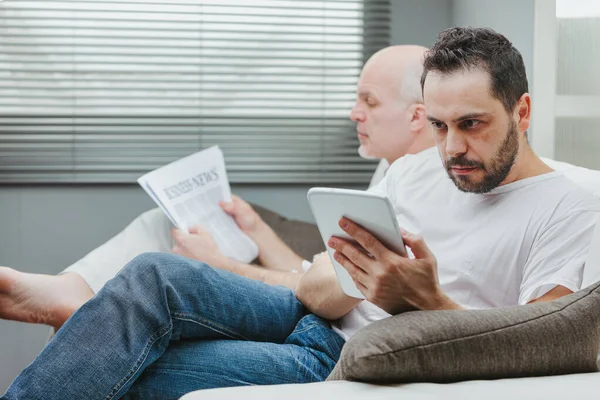 Homem Sentado Lado Seu Pai Idoso Sofá Lendo Tablet Com — Fotografia de Stock