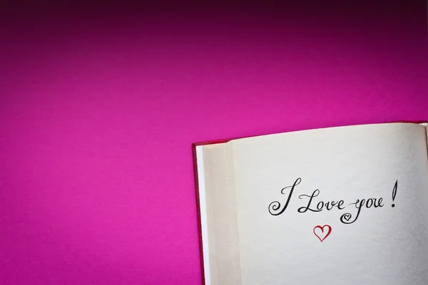 Me encantan las palabras en el libro abierto con fondo rosa y copiar el espacio para su texto. Concepto de declaración de amor. También es bueno para la postal . — Foto de Stock