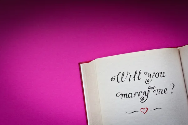 Wirst du mich heiraten? Worte und rotes Herz im aufgeschlagenen Buch. mit Liebe erschaffen. — Stockfoto
