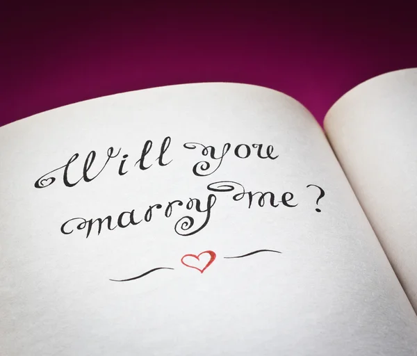 Wirst du mich heiraten? Worte und rotes Herz im aufgeschlagenen Buch. mit Liebe erschaffen. — Stockfoto