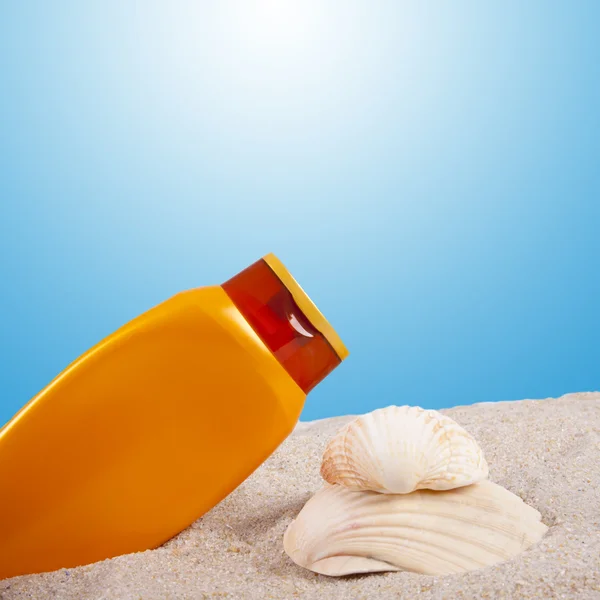 Lozione abbronzante e conchiglie sulla spiaggia — Foto Stock