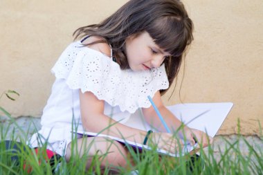 Not defterinde renkli kalemlerle sırt çantasıyla resim yapan öğrenci kız okula geri dönüyor.