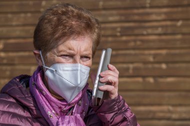 Son sınıf öğrencisi kadın yeni normaliyle sokakta cep telefonu kullanıyor.