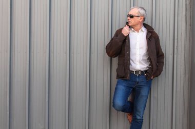 Duvarda kot pantolon ve ceket giyen yetişkin bir adam.