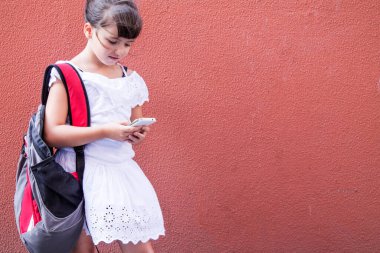 Sırt çantalı kız duvar arkası cep telefonu kullanıyor