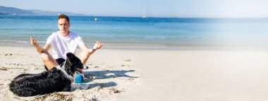 Sahilde köpeğiyle yoga yapan bir adam fotokopi çekerek rahatlıyor.