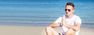 Plajda rahat bir adam fotokopi uzayı ile yoga yapıyor.