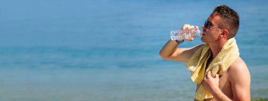 Sahildeki adam dinlenmekten ve su içmekten yoruldu.