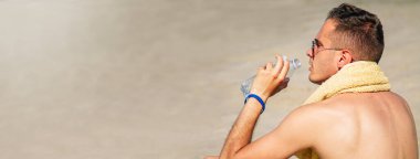 Sahildeki adam dinlenmekten ve su içmekten yoruldu.