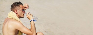 Sahildeki adam dinlenmekten ve su içmekten yoruldu.