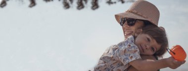 Annesinin kollarında balkabağı olan ve fotokopi çeken bir çocuk.