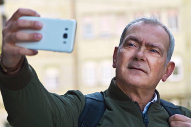 Turist adam sokakta akıllı telefonuyla selfie çekiyor.