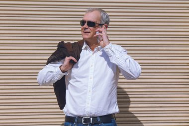 Görme engelli cep telefonuyla konuşan zarif, olgun bir adam.