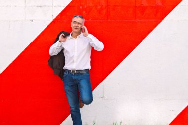 Duvarda cep telefonu kullanan orta yaşlı bir adam.