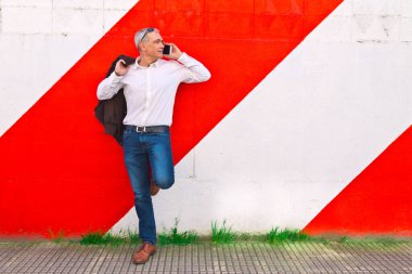 Duvarda cep telefonu kullanan orta yaşlı bir adam.