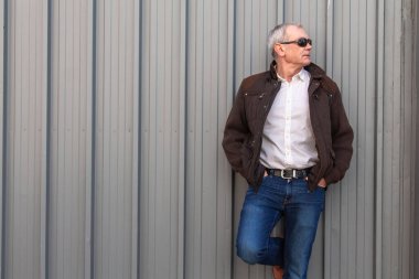 Duvarda kot pantolon ve ceket giyen yetişkin bir adam.