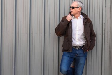 Duvarda kot pantolon ve ceket giyen yetişkin bir adam.