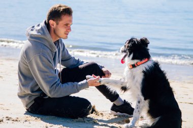 Plajda köpeğiyle genç bir adamın portresi.