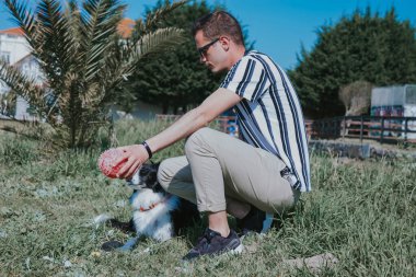 Parktaki güneş gözlüklü ve köpeğinin portresi.