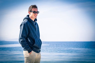 Genç adam sahilde yürüyor.