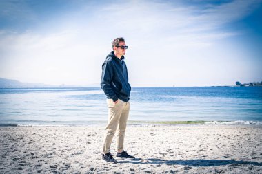 Genç adam sahilde yürüyor.