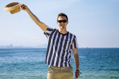 Uzanmış kolları ve şapkası kumsalda olan tatmin olmuş ve rahat bir adam.