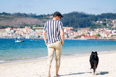 Sahilde köpeğiyle yürüyen adam