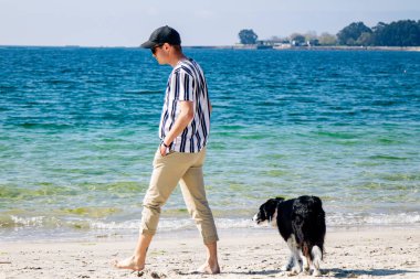 Sahilde köpeğiyle yürüyen adam