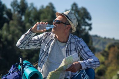 Dağcı içmek için mola veriyor ve haritaya bakıyor.