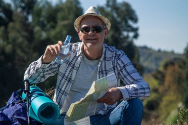 Dağcı içmek için mola veriyor ve haritaya bakıyor.