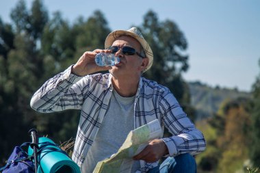 Dağcı içmek için mola veriyor ve haritaya bakıyor.