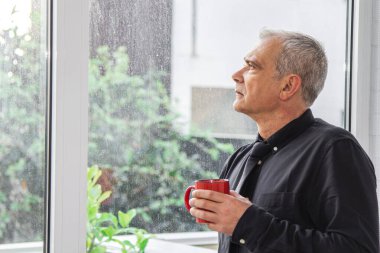 Yetişkin bir adam ofiste ya da evde kahve içiyor.