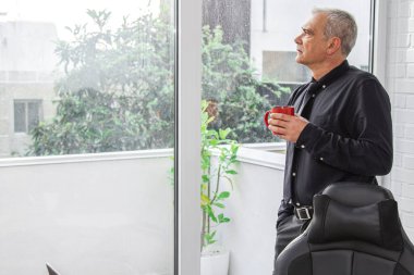 Yetişkin bir adam ofiste ya da evde kahve içiyor.