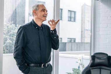 Evde ya da ofiste telefonuyla konuşan orta yaşlı bir adam.