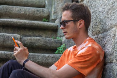 Genç adam merdivenlerde cep telefonu kullanıyor.