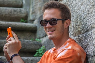 Genç adam merdivenlerde cep telefonu kullanıyor.