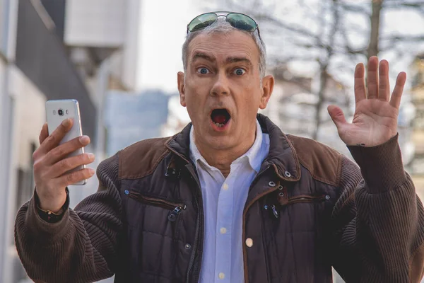 Mann Mit Überraschungsgeste Blickt Auf Handy Auf Der Straße — Stockfoto