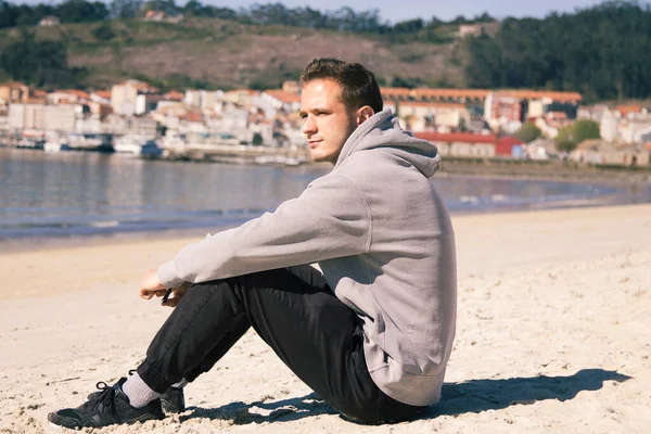 Gülümseyen genç adam rahatlamış ve sahilde eğleniyor.