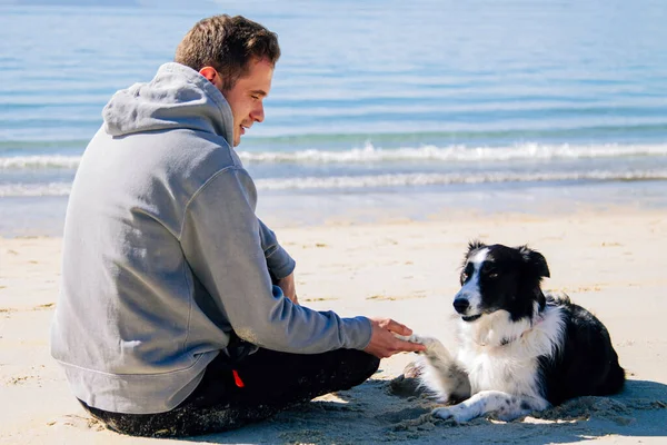 Plajda köpeğiyle genç bir adamın portresi.