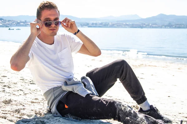 Gülümseyen genç adam rahatlamış ve sahilde eğleniyor.