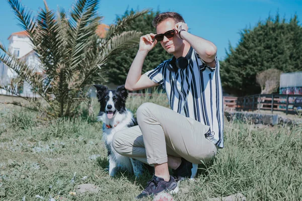 Parktaki güneş gözlüklü ve köpeğinin portresi.