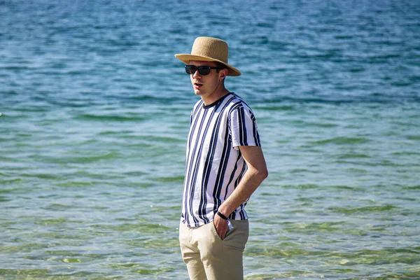 Genç adam sahilde yürüyor.