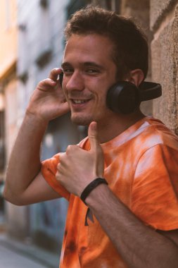 Kulaklıklı genç adam elle imza atıyor.