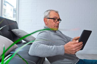 Mutlu rahat adam dijital tabletini kullanıyor.